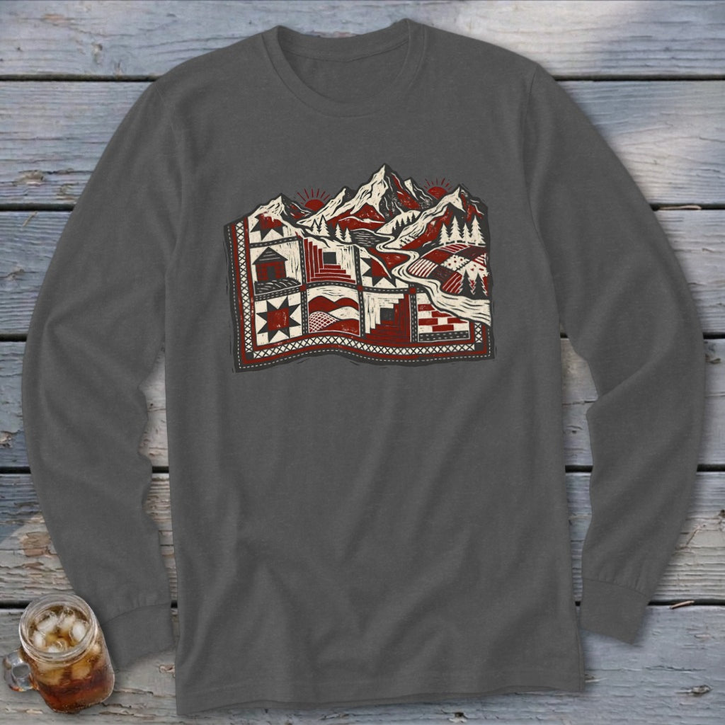 A charcoal grey long-sleeve t-shirt with a red, black, and white graphic of a quilt featuring mountains, suns, trees, and cabins.