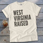 Cream t-shirt with "WEST VIRGINIA RAISED" printed in dark gray.