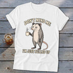 White t-shirt with a grumpy possum holding coffee and text "DON'T MIND ME I'M JUST SULLED UP."