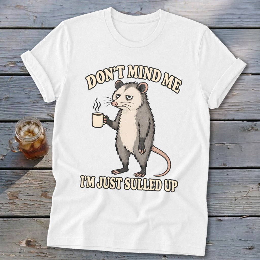 White t-shirt with a grumpy possum holding coffee and text "DON'T MIND ME I'M JUST SULLED UP."