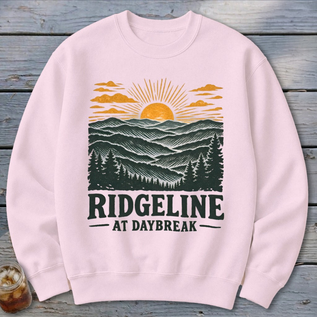 Light pink sweatshirt with "RIDGELINE AT DAYBREAK" and mountain sunrise graphic.