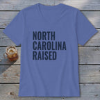 Purple v-neck t-shirt with dark grey text "NORTH CAROLINA RAISED".
