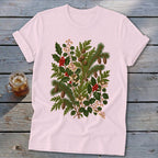 Light pink t-shirt with a green botanical illustration of holly, pine, and pinecones.