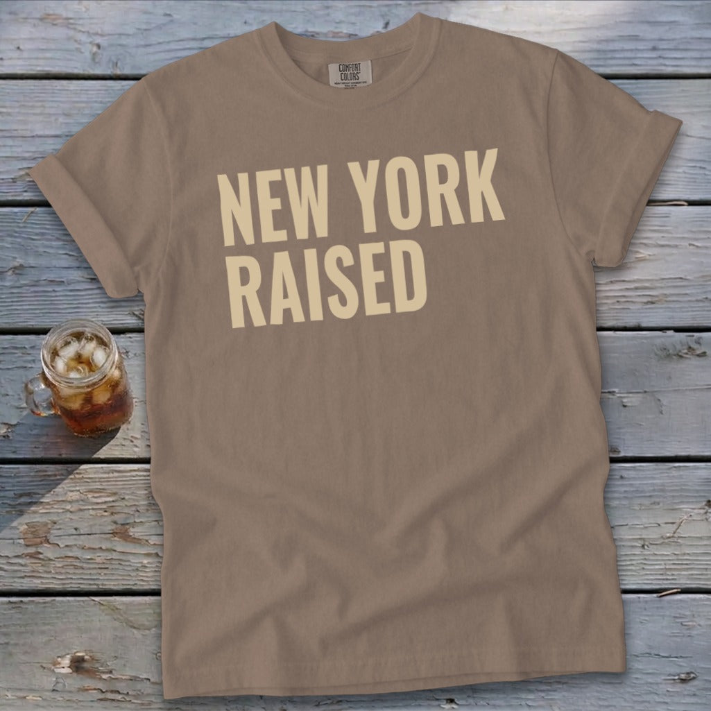 Brown t-shirt with "NEW YORK RAISED" text in cream letters.