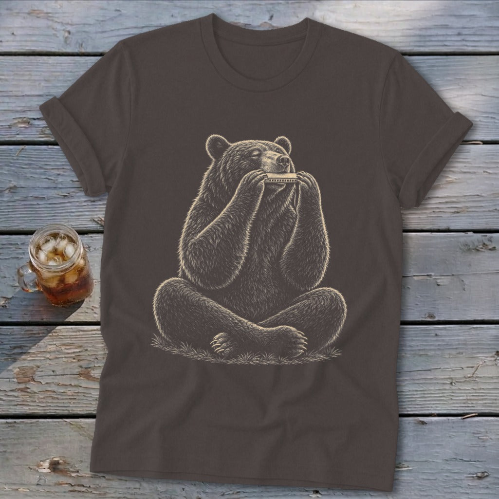 Bear sitting cross-legged, playing a harmonica on a dark brown t-shirt.