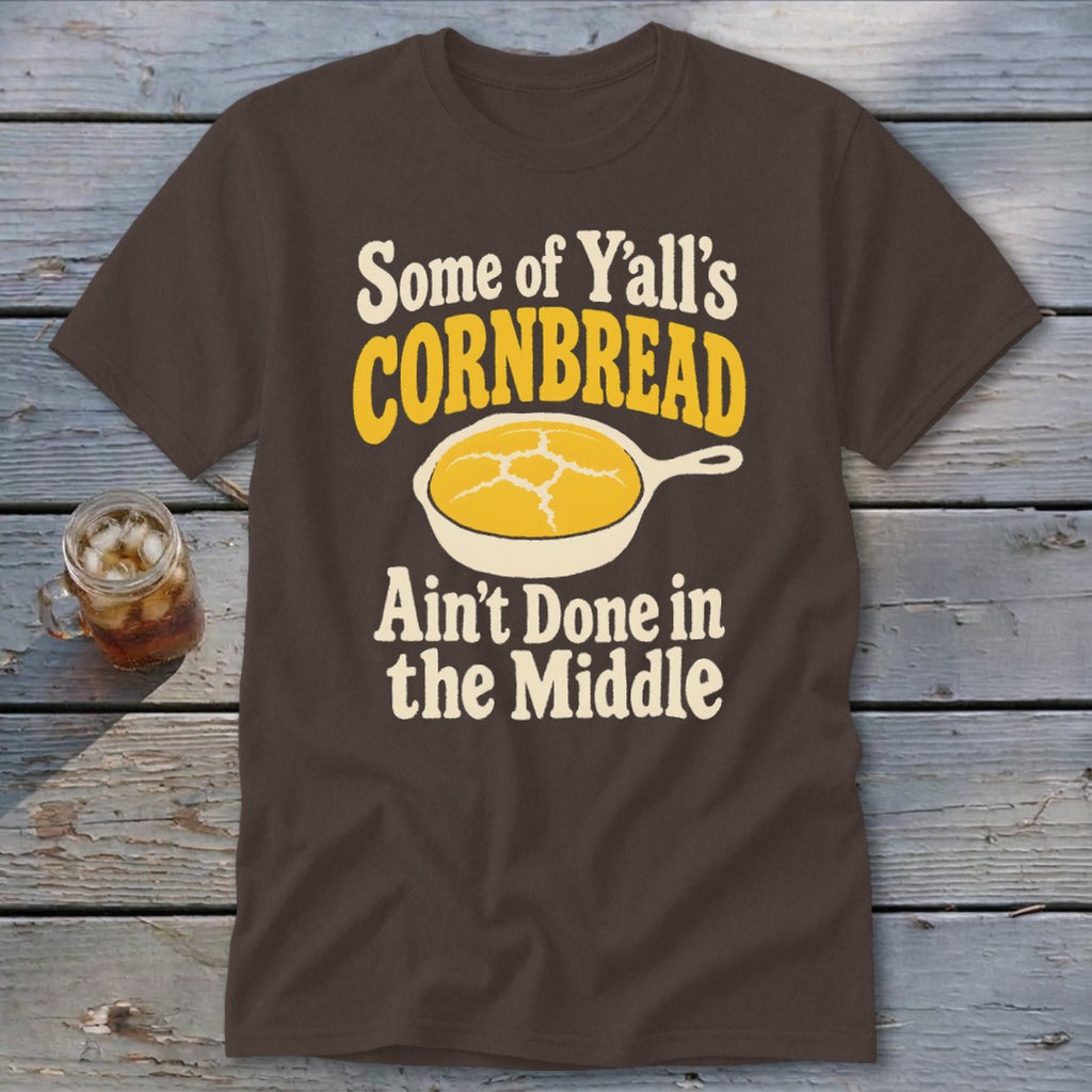 Brown t-shirt featuring the text "Some of Y'all's Cornbread Ain't Done in the Middle" and a skillet graphic.