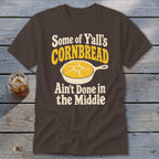 Brown t-shirt featuring the text "Some of Y'all's Cornbread Ain't Done in the Middle" and a skillet graphic.