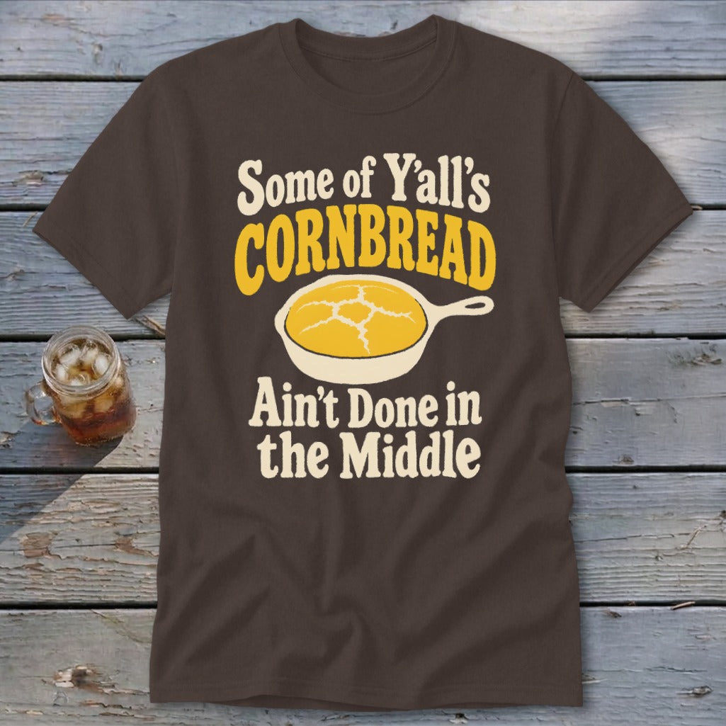Brown t-shirt featuring the text "Some of Y'all's Cornbread Ain't Done in the Middle" and a skillet graphic.
