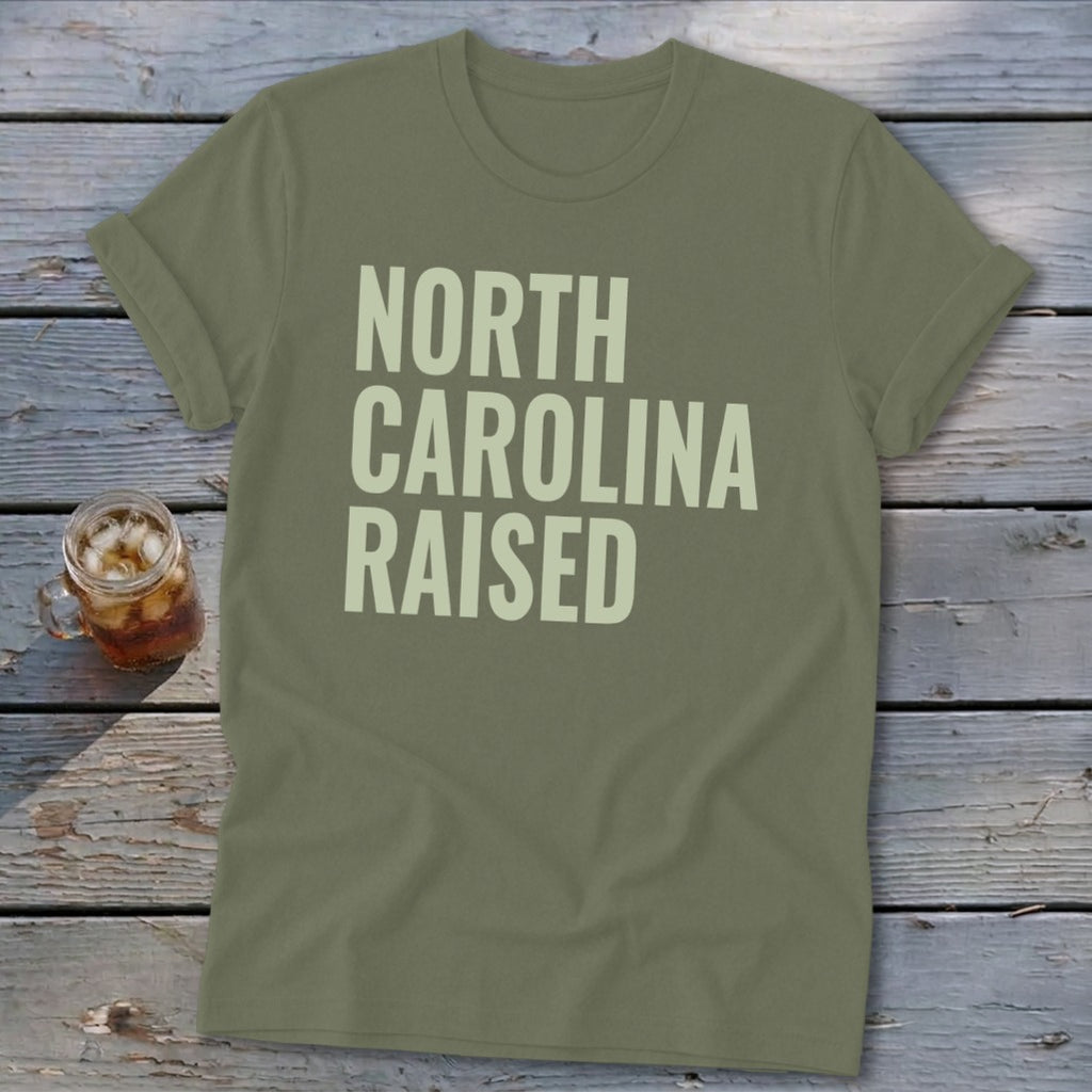 Olive green t-shirt with "NORTH CAROLINA RAISED" text in light beige.