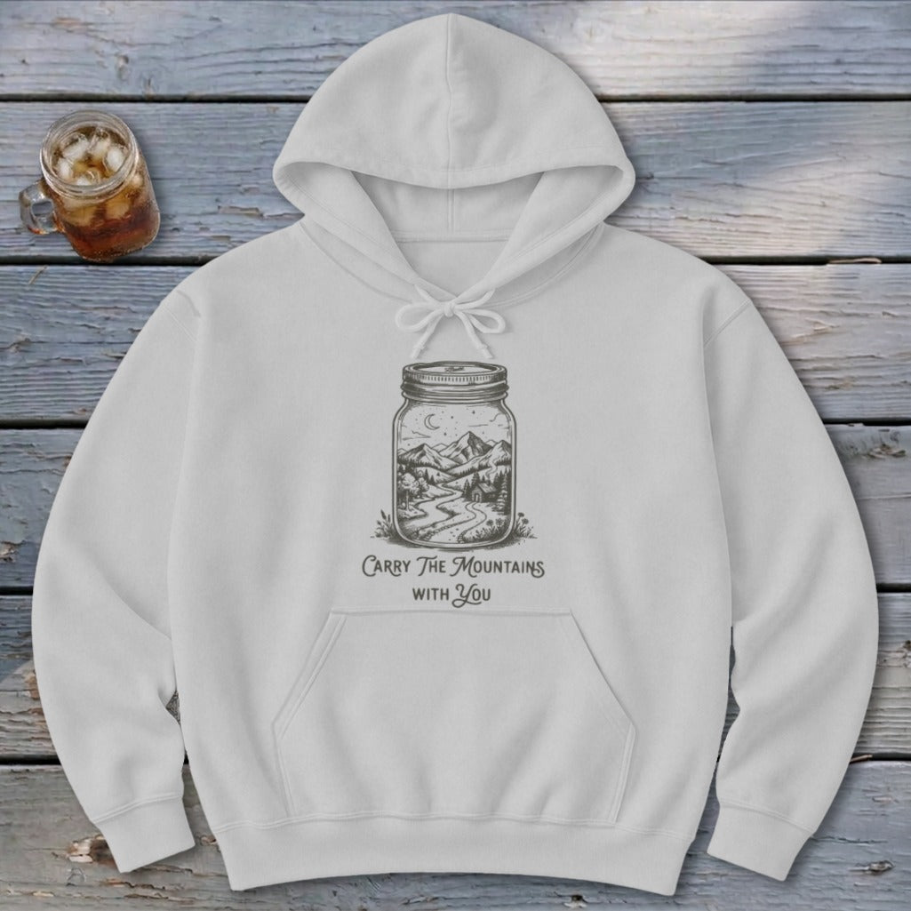 A white pullover hoodie features a mason jar illustration containing a mountain scene and text reading Carry The Mountains With You.
