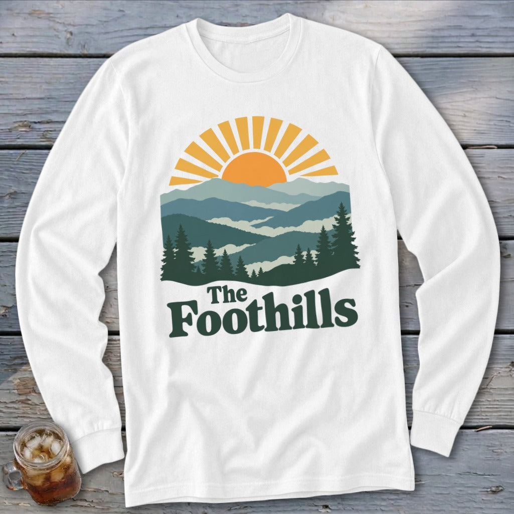 White long-sleeve shirt with "The Foothills" text and a mountain landscape graphic.