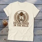 Cream t-shirt with a brown emblem featuring a lantern, gears, and laurel leaves above text.