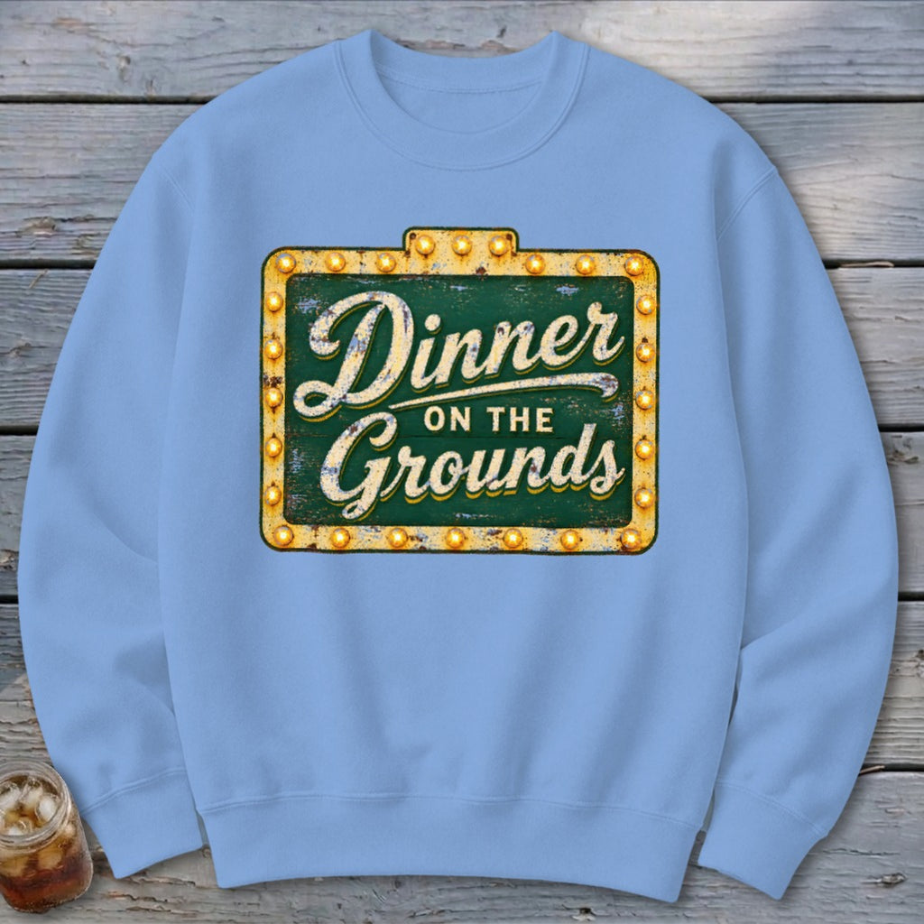 Light blue crewneck sweatshirt featuring a graphic of a lighted sign that reads Dinner on the Grounds.