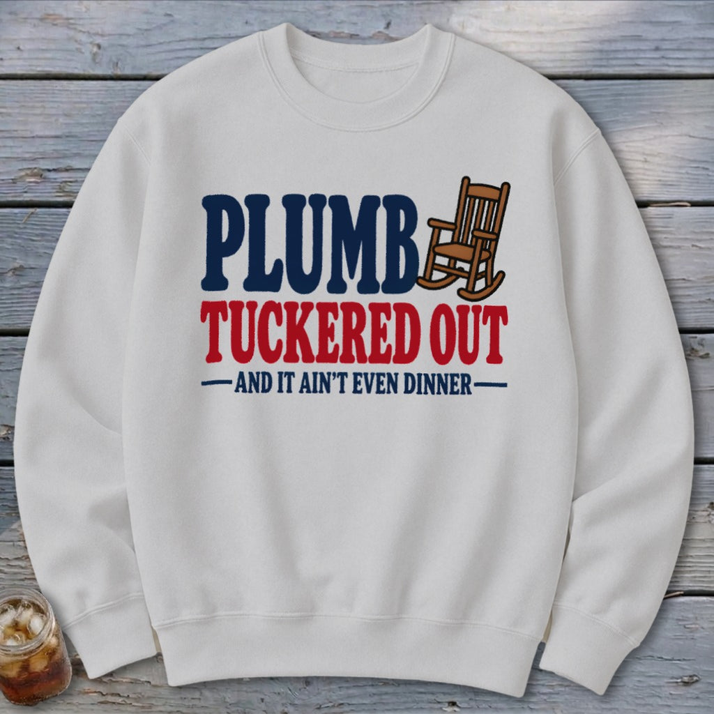White sweatshirt with "PLUMBER TUCKERED OUT" text and rocking chair graphic.