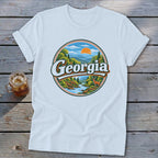 White t-shirt with a circular graphic of a Georgia landscape featuring a river, deer, and mountains.