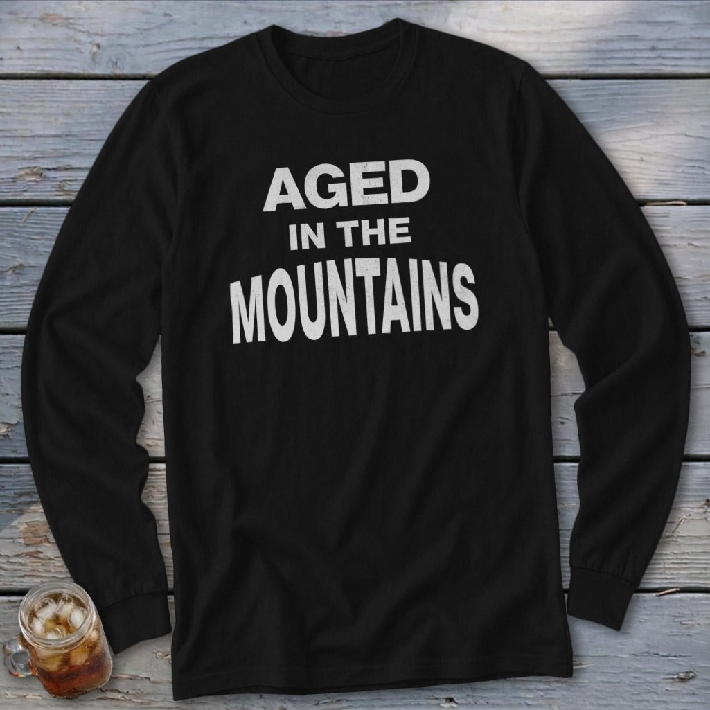 Black long-sleeved shirt with white text reading "AGED IN THE MOUNTAINS."