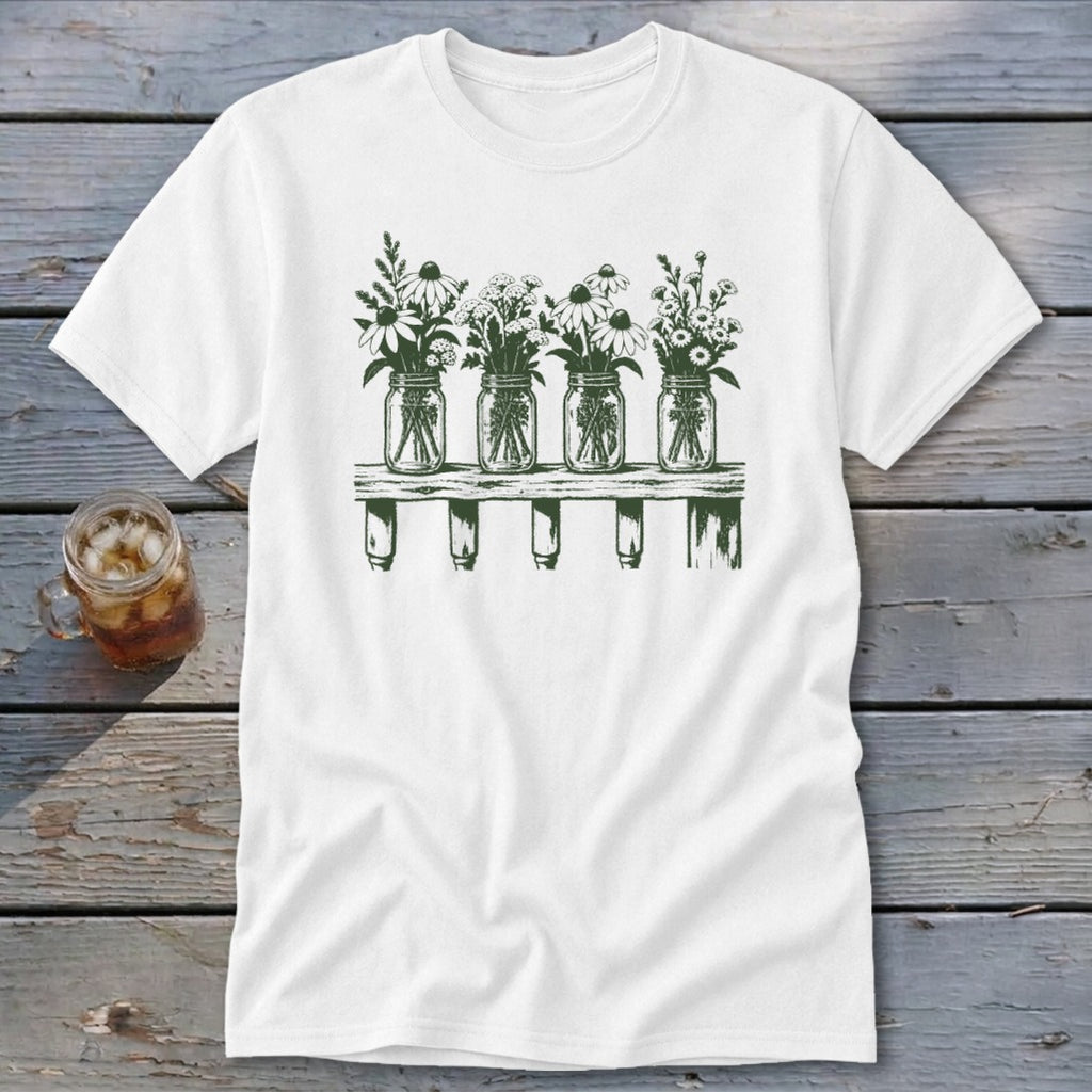 A white t-shirt featuring a green graphic of four mason jars filled with wildflowers on a shelf.