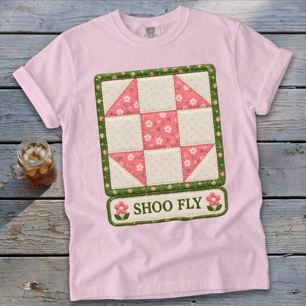 Pink t-shirt with a quilted "Shoo Fly" graphic featuring pink and white squares and floral accents.