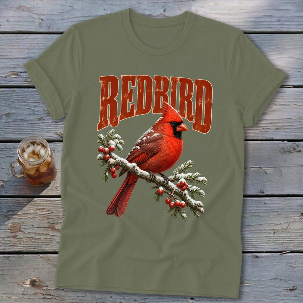 An olive green t-shirt features a graphic of a red cardinal on a snowy branch with the text REDBIRD.