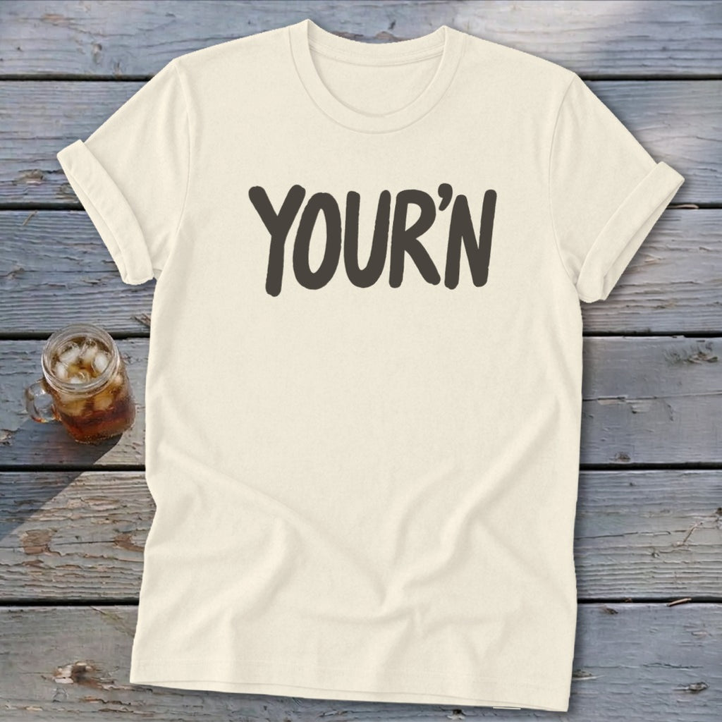 Cream t-shirt with bold dark gray text "YOUR'N" across the chest.