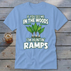 Light blue t-shirt featuring graphic text and three wild leeks, displayed on a wooden surface.