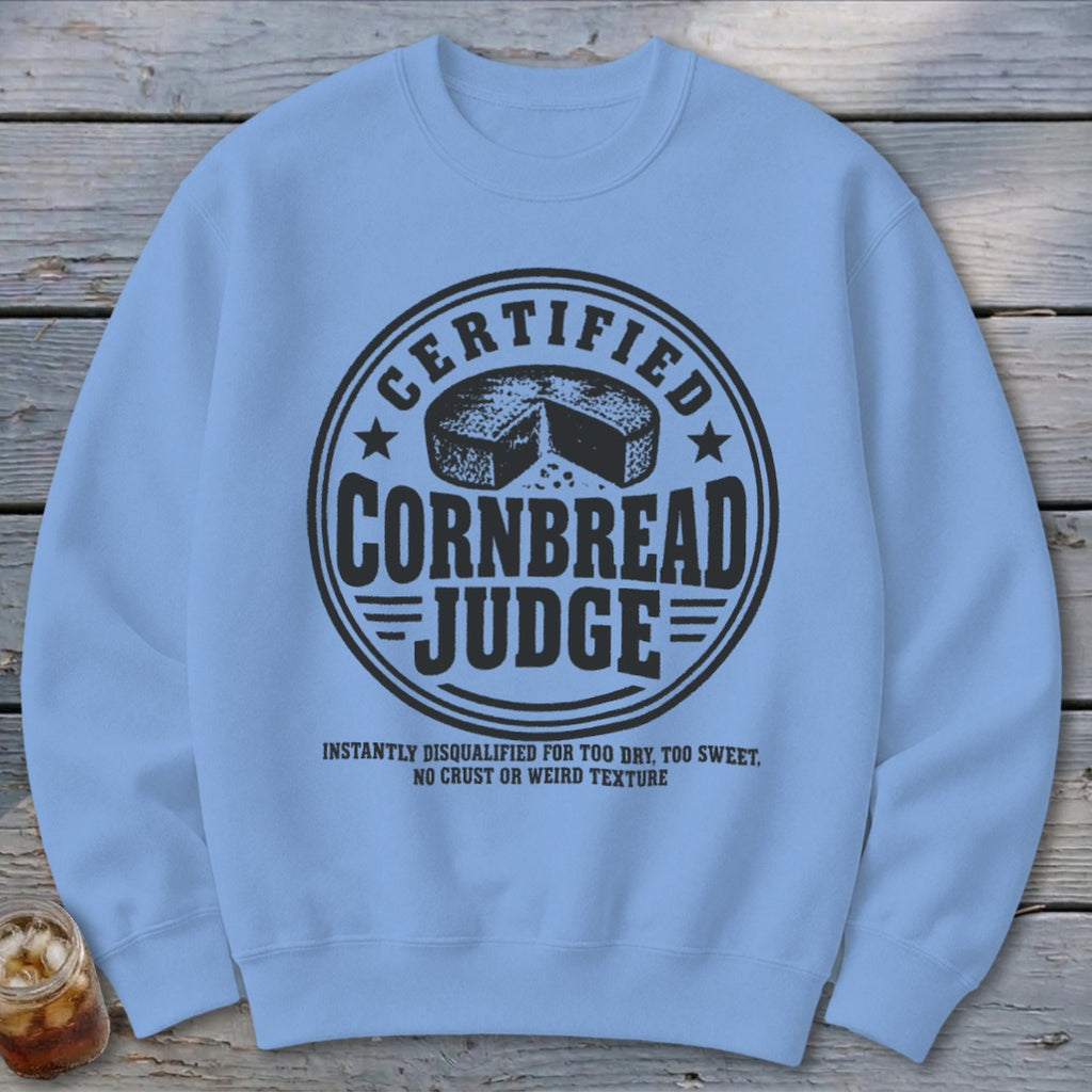 A light blue crewneck sweatshirt featuring a black graphic that reads Certified Cornbread Judge.