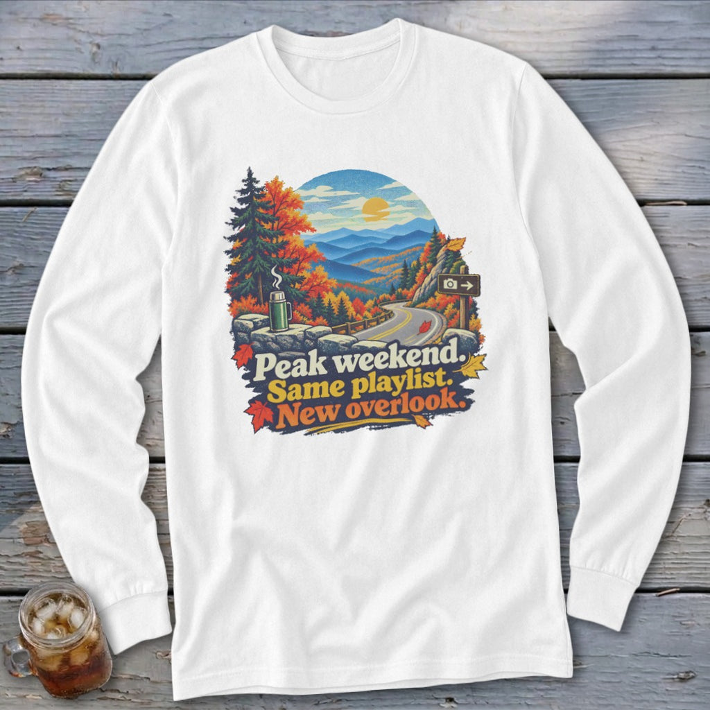 White long-sleeve shirt with a graphic of a scenic overlook with text "Peak weekend. Same playlist. New overlook."
