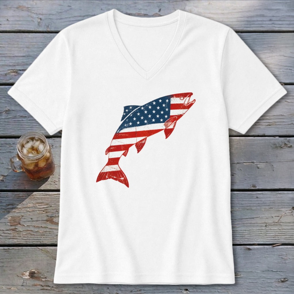 White V-neck t-shirt featuring a distressed American flag fish graphic laid flat on weathered wood.