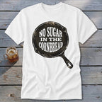 White t-shirt with graphic of a cast iron skillet saying "NO SUGAR IN THE CORNBREAD."