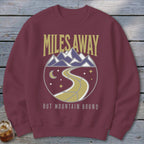 Maroon sweatshirt with "Miles Away But Mountain Bound" text and mountain graphic.