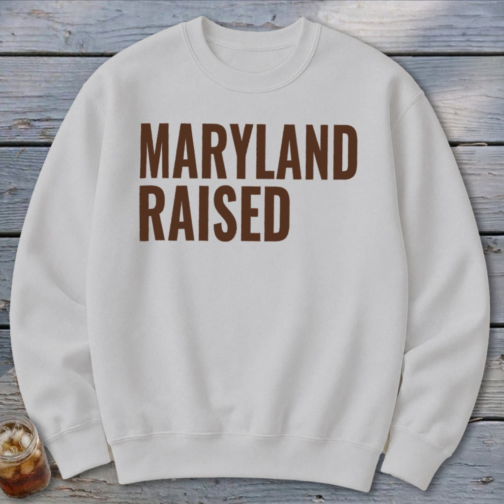 White sweatshirt with "MARYLAND RAISED" text in brown.