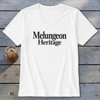 White V-neck t-shirt with the black text Melungeon Heritage displayed centrally on a wooden background.