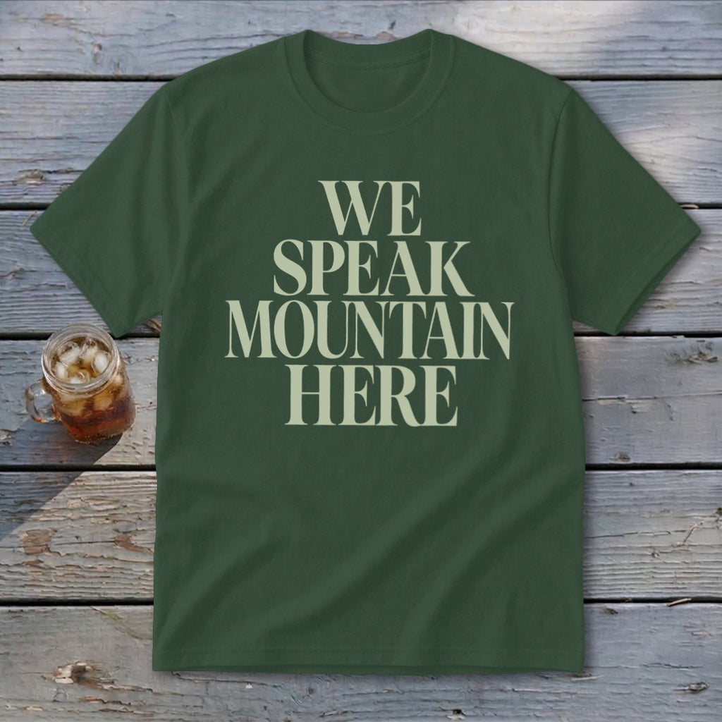 Green t-shirt with "WE SPEAK MOUNTAIN HERE" text in off-white font.