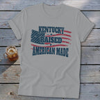 Grey t-shirt with "Kentucky Raised American Made" text over a distressed American flag design.