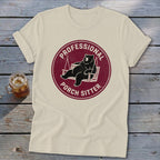 Cream-colored t-shirt featuring a maroon circular graphic of a bear lounging on a porch swing, with text reading Professional Porch Sitter.