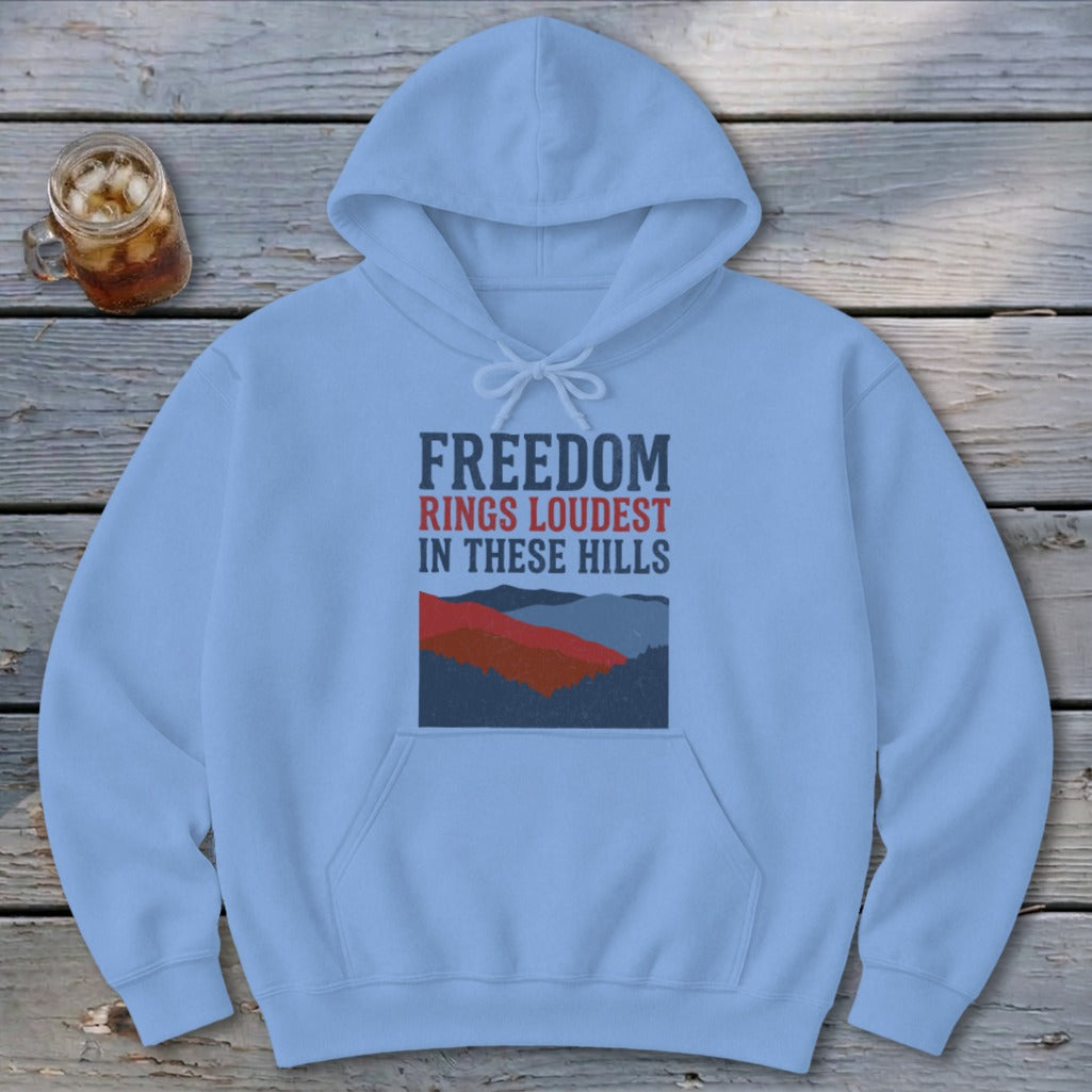 Light blue hooded sweatshirt featuring the text Freedom Rings Loudest in These Hills above a mountain graphic.
