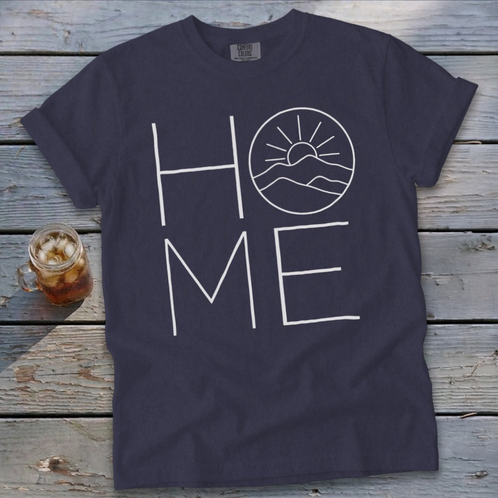 Navy blue crewneck t-shirt featuring the word HOME in white, with a mountain and sun graphic replacing the letter O.