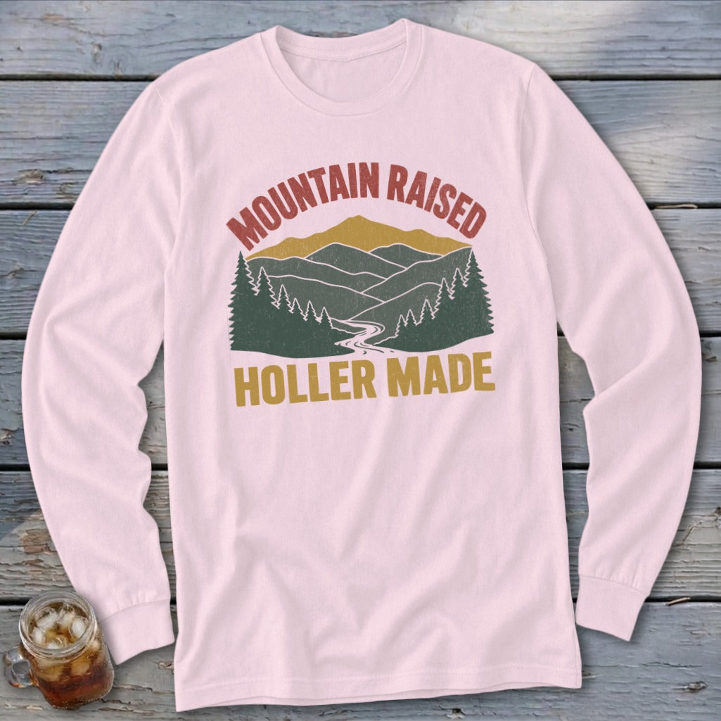 Light pink long-sleeve t-shirt with a vintage mountain graphic and the text Mountain Raised Holler Made.
