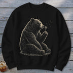 Black sweatshirt featuring a detailed illustration of a bear blowing on a dandelion.