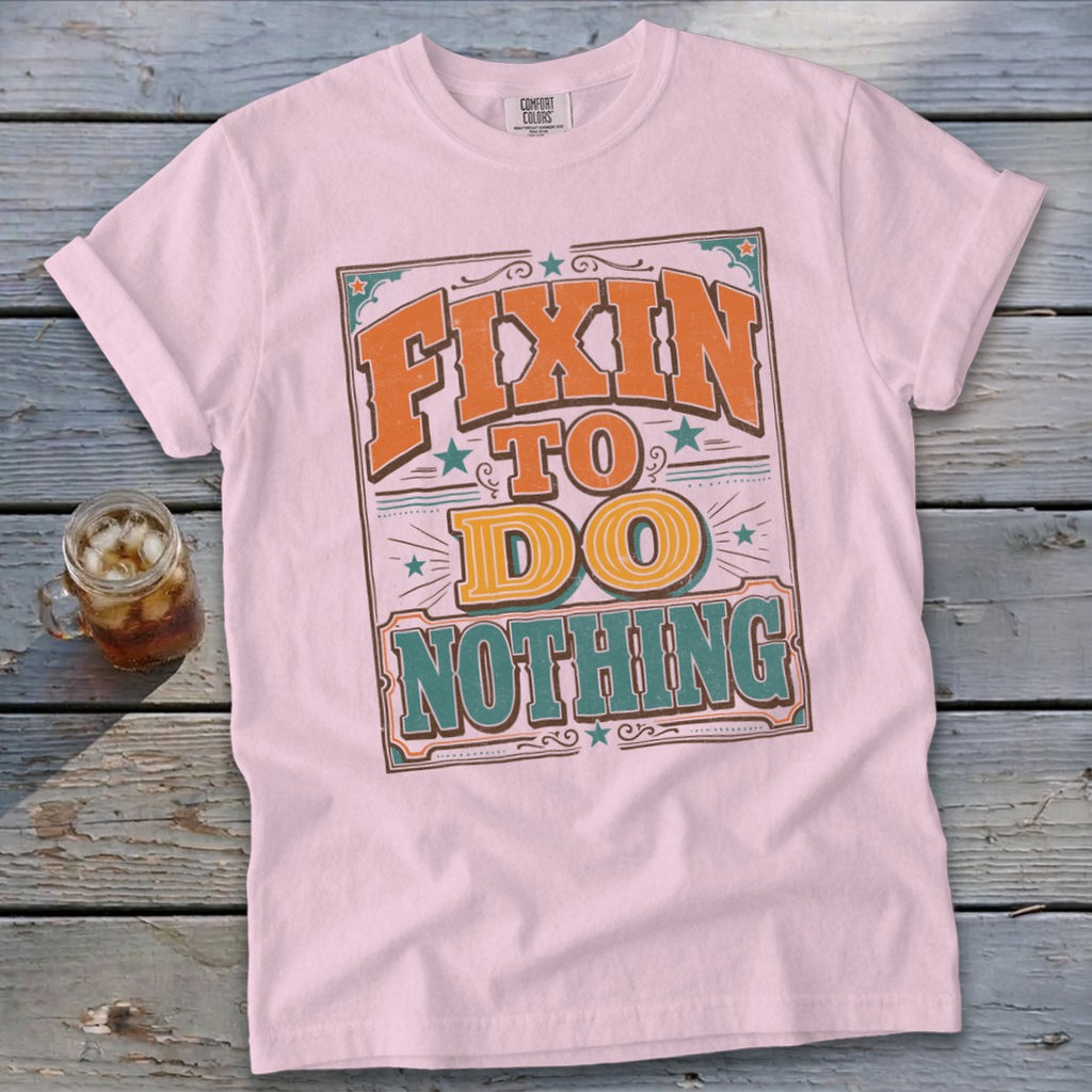 Pink t-shirt with "Fixin' To Do Nothing" text in orange and teal vintage lettering.