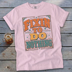 Pink t-shirt with "Fixin' To Do Nothing" text in orange and teal vintage lettering.