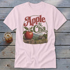 Light pink t-shirt featuring a retro graphic of an apple, a cabin, and mountains with the text Apple At Cha.