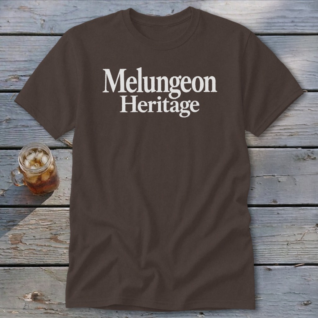 Brown t-shirt featuring the white text Melungeon Heritage centered on the chest, displayed on weathered wood planks.