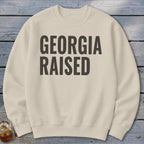 Cream sweatshirt with bold black text that reads "GEORGIA RAISED".