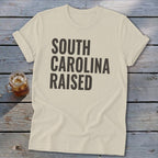 Cream t-shirt with "South Carolina Raised" text in dark gray.