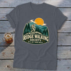 T-shirt graphic with hiker on ridge, mountains, sun, and text "Ridge Walking Society".