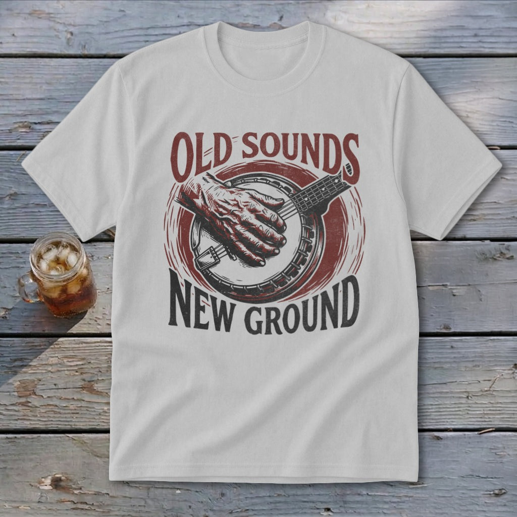 A light gray t-shirt with a vintage graphic of a hand playing a banjo and text reading Old Sounds New Ground.