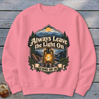 Pink sweatshirt with a graphic of a lantern and mountains, reading "Always Leave the Light On Come On In".