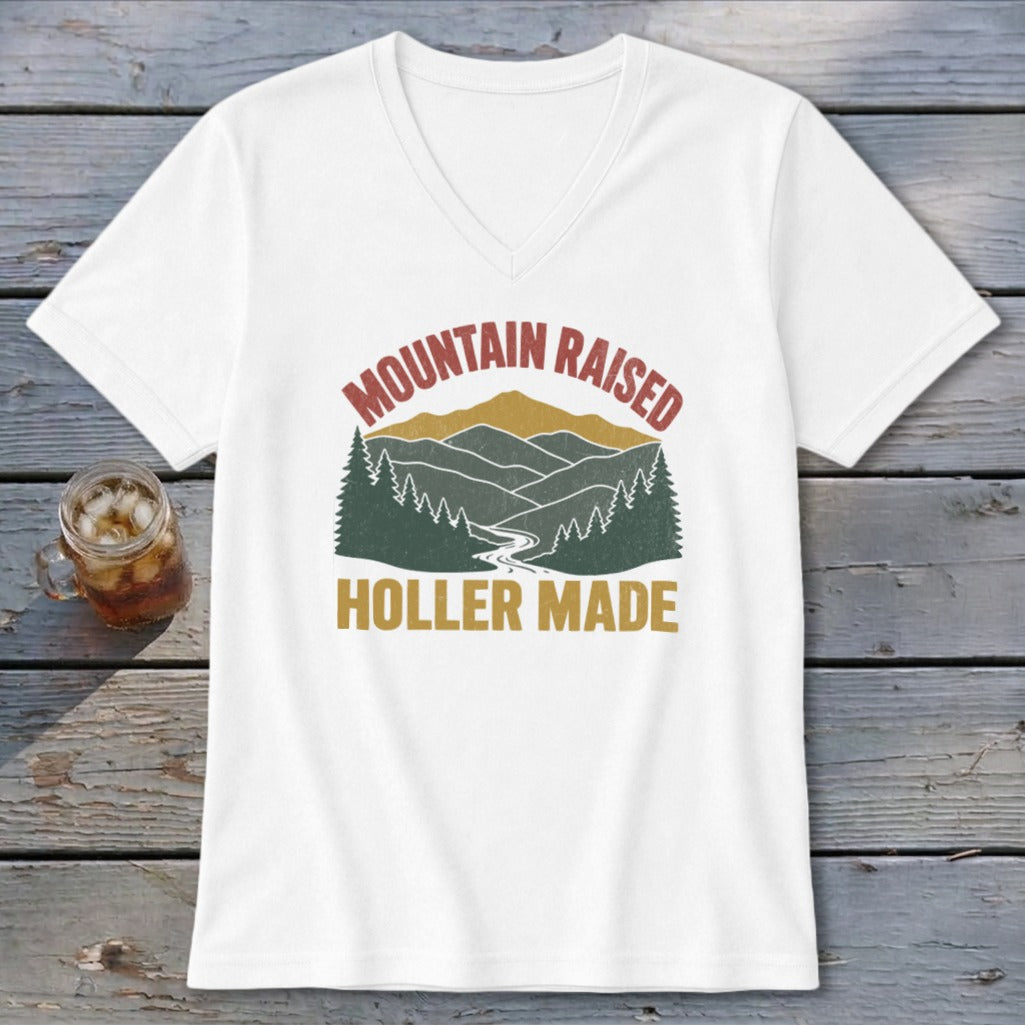 A white V-neck t-shirt featuring a retro mountain graphic with the text Mountain Raised and Holler Made.