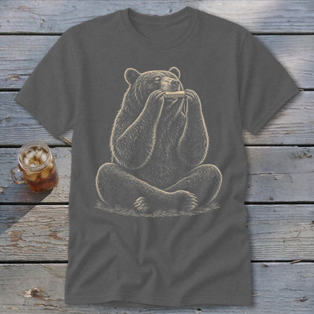 Bear playing a harmonica, seated cross-legged on grass, on a grey t-shirt.
